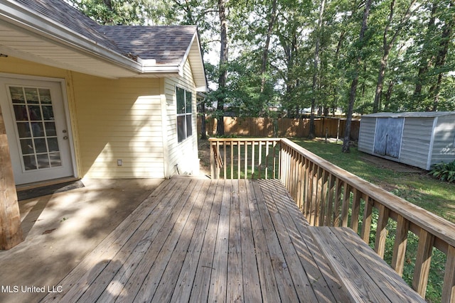 deck with a fenced backyard, a storage unit, and an outbuilding