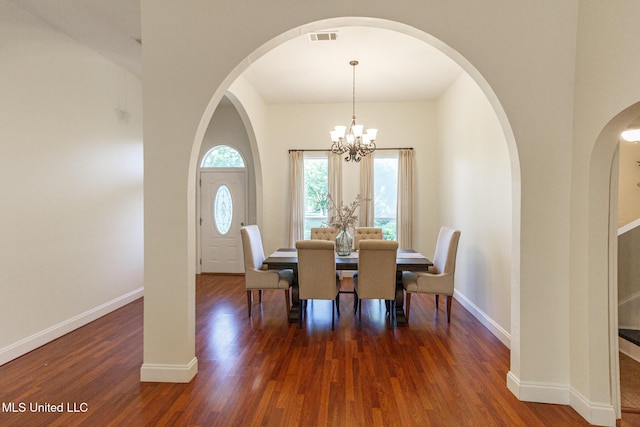dining area featuring arched walkways, baseboards, visible vents, and wood finished floors