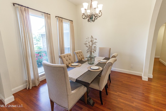 dining space with arched walkways, baseboards, a chandelier, and wood finished floors