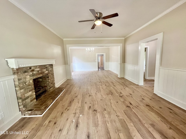 708 Lee Ave, Crystal Springs, MS 39059 - unfurnished living room featuring wood finished floors, ceiling fan, a brick fireplace, wainscoting, and a chandelier
