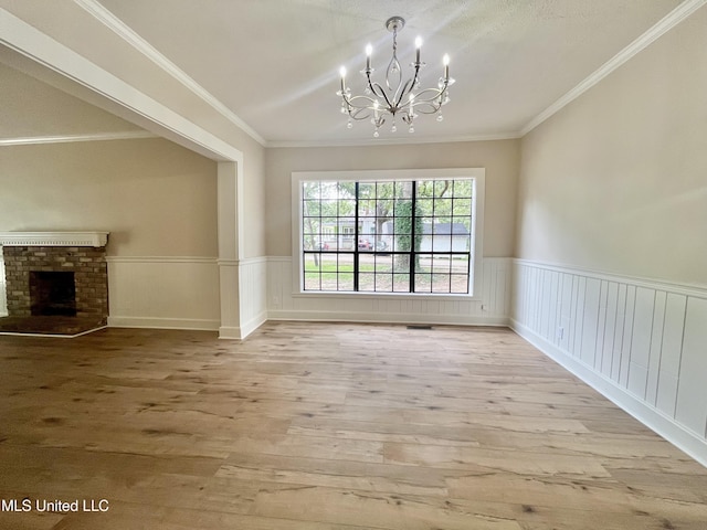 708 Lee Ave, Crystal Springs, MS 39059 - unfurnished dining area with light wood-style floors, a chandelier, wainscoting, ornamental molding, and a fireplace