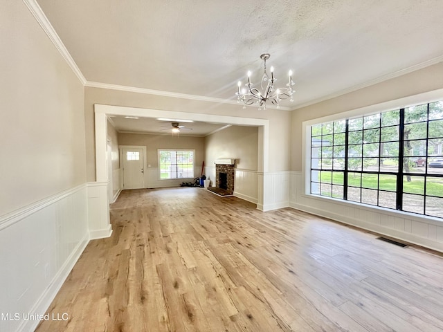 708 Lee Ave, Crystal Springs, MS 39059 - unfurnished living room featuring a chandelier, light wood-style flooring, ornamental molding, a wainscoted wall, and a brick fireplace