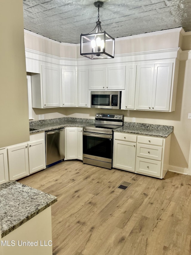 708 Lee Ave, Crystal Springs, MS 39059 - kitchen featuring stainless steel appliances, a chandelier, white cabinetry, light wood finished floors, and an ornate ceiling