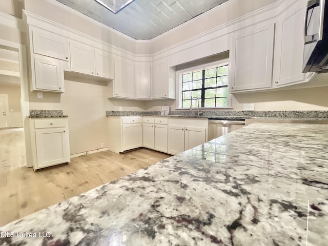 708 Lee Ave, Crystal Springs, MS 39059 - kitchen with light stone countertops, light wood-style floors, white cabinets, and dishwasher