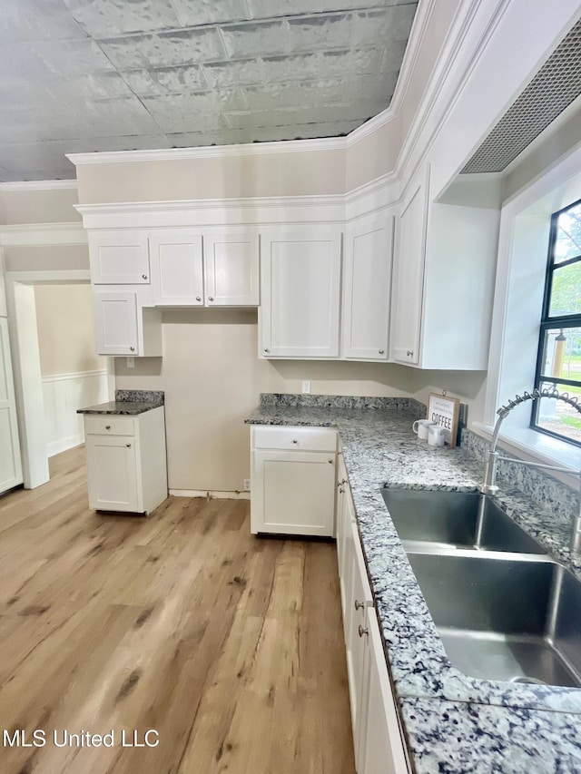 708 Lee Ave, Crystal Springs, MS 39059 - kitchen with light wood finished floors, white cabinetry, stone counters, and crown molding