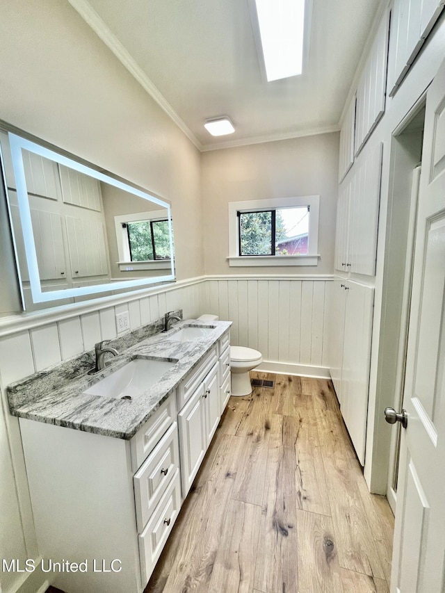 708 Lee Ave, Crystal Springs, MS 39059 - full bath featuring wood finished floors, a wainscoted wall, crown molding, double vanity, and healthy amount of natural light