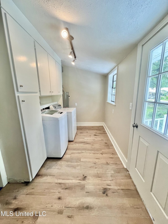 708 Lee Ave, Crystal Springs, MS 39059 - laundry area featuring light wood finished floors, separate washer and dryer, cabinet space, and a textured ceiling