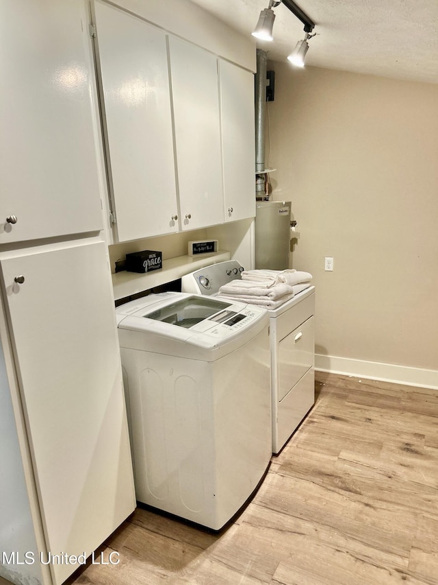 708 Lee Ave, Crystal Springs, MS 39059 - laundry area featuring cabinet space, washer and clothes dryer, light wood-type flooring, and water heater
