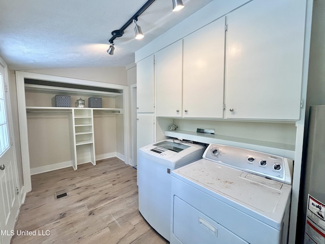 708 Lee Ave, Crystal Springs, MS 39059 - laundry area featuring cabinet space, washer and clothes dryer, light wood-type flooring, a textured ceiling, and water heater