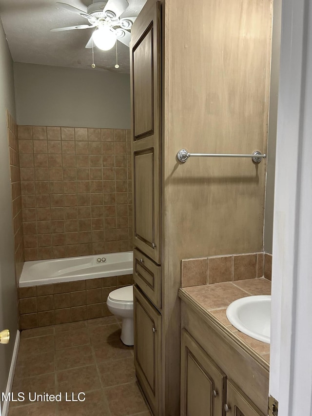 bathroom featuring tile patterned floors, vanity, ceiling fan, tiled bath, and toilet