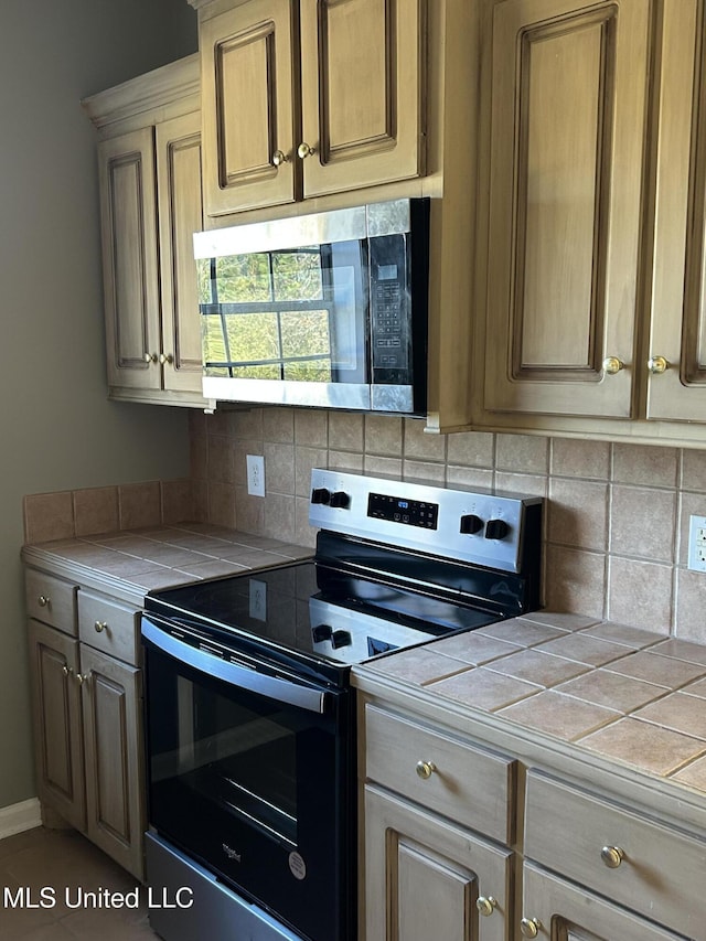 kitchen featuring appliances with stainless steel finishes, tasteful backsplash, and tile counters