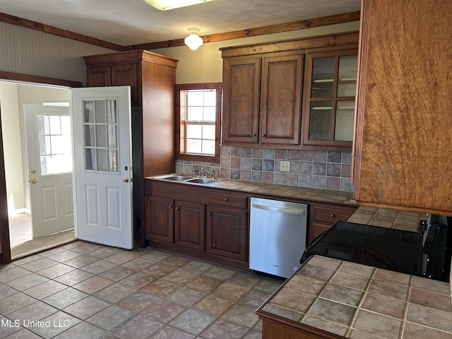 kitchen featuring tasteful backsplash, sink, dishwasher, range, and tile counters