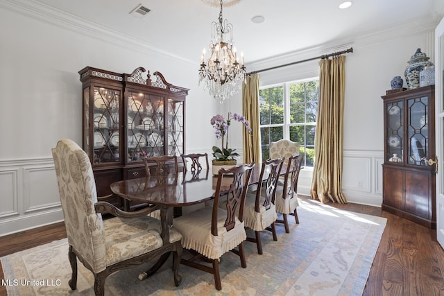 dining area featuring visible vents, ornamental molding, wood finished floors, a wainscoted wall, and a notable chandelier