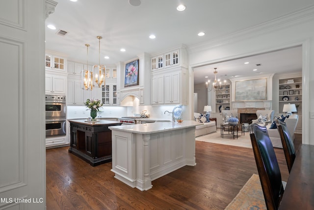 kitchen with dark wood-type flooring, stainless steel double oven, open floor plan, and a chandelier