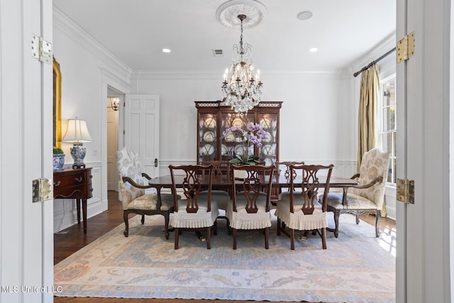 dining space featuring visible vents, crown molding, wood finished floors, and a notable chandelier