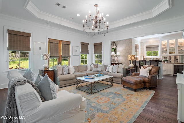 living area featuring visible vents, a raised ceiling, beverage cooler, a notable chandelier, and a wealth of natural light