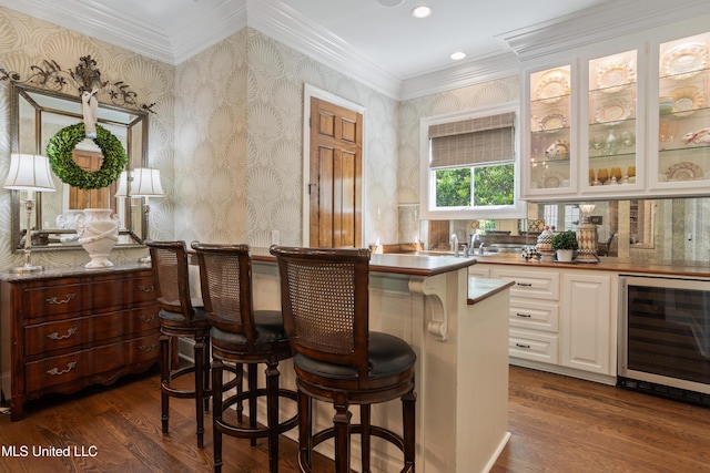 bar with crown molding, dark wood-style flooring, wine cooler, and bar area