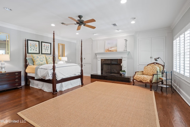 bedroom with crown molding, a fireplace with raised hearth, dark wood-type flooring, and visible vents