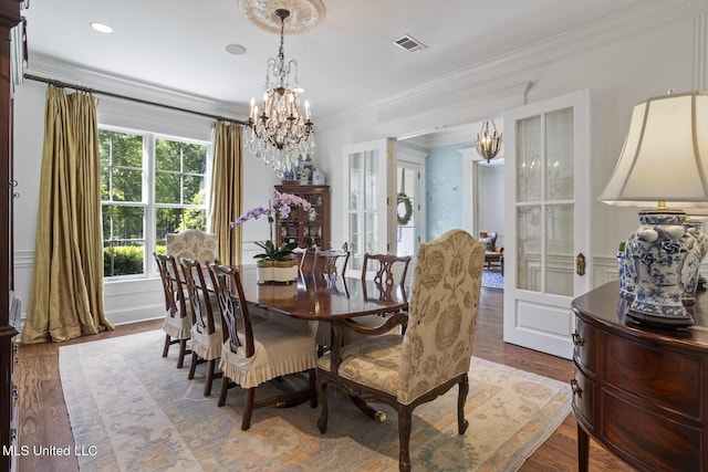 dining space featuring crown molding, visible vents, wood finished floors, and a notable chandelier