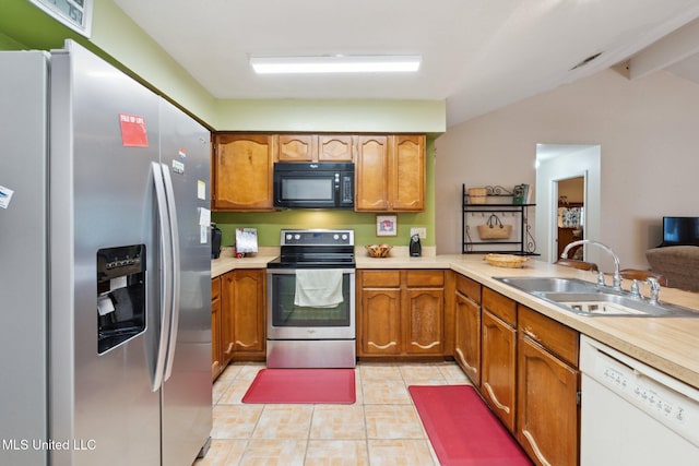 6944 Apona St, Diamondhead, MS 39525 - kitchen with appliances with stainless steel finishes, a sink, light tile patterned floors, brown cabinetry, and light countertops