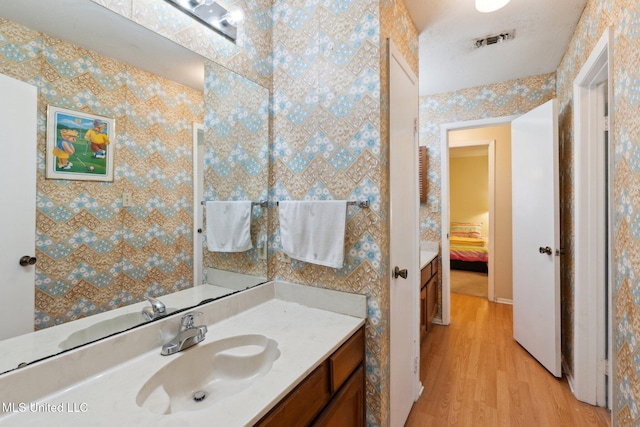 6944 Apona St, Diamondhead, MS 39525 - bathroom featuring wood finished floors, vanity, and connected bathroom