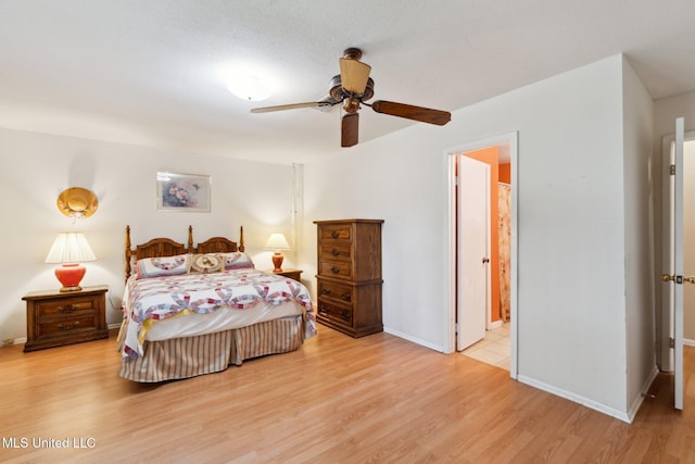 6944 Apona St, Diamondhead, MS 39525 - bedroom featuring light wood-style flooring, baseboards, ensuite bath, and a ceiling fan