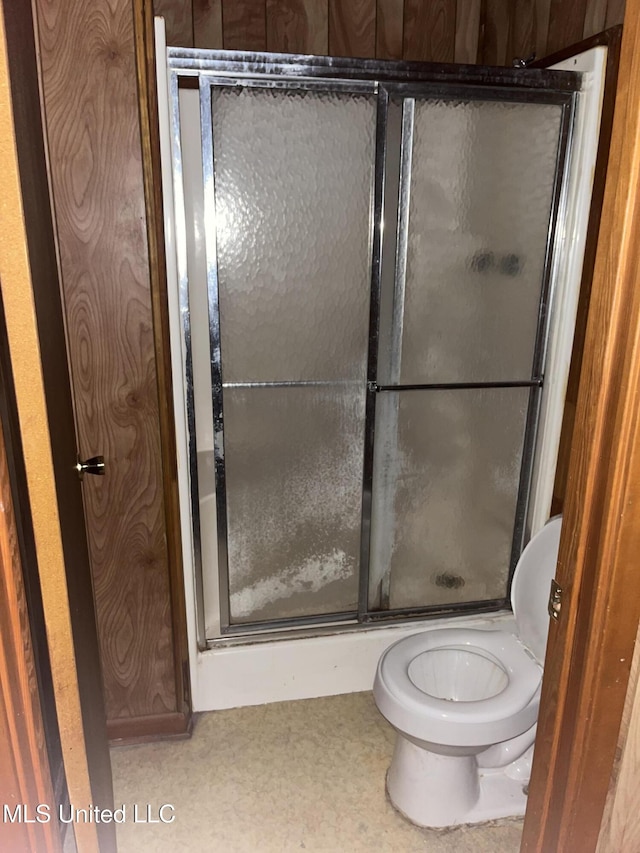 bathroom with a shower with door and toilet
