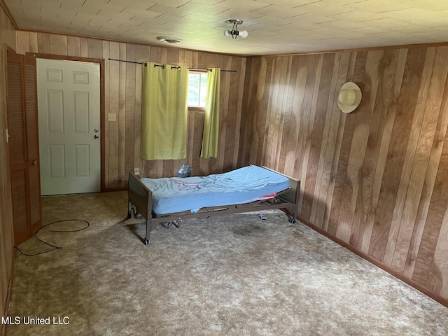carpeted bedroom featuring wooden walls
