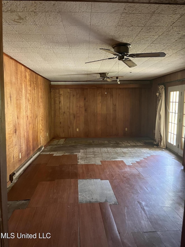 empty room featuring ceiling fan, wooden walls, and dark hardwood / wood-style flooring
