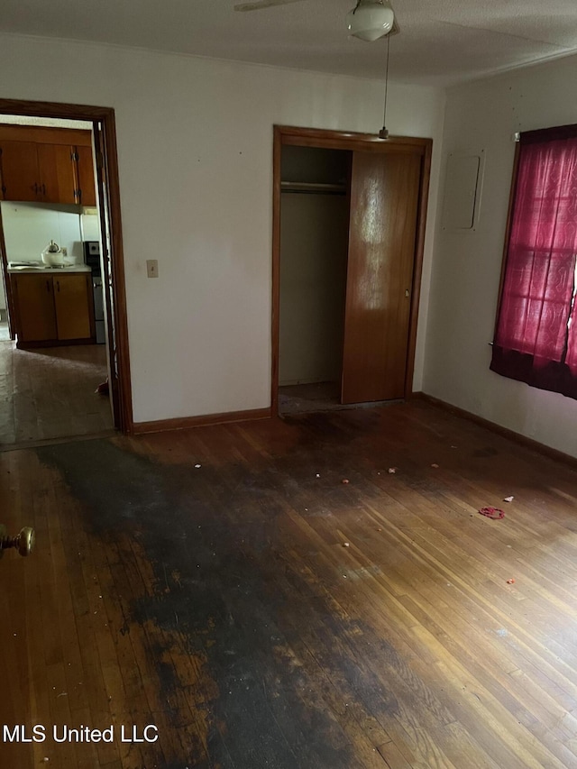 unfurnished bedroom featuring hardwood / wood-style floors, electric panel, and a closet
