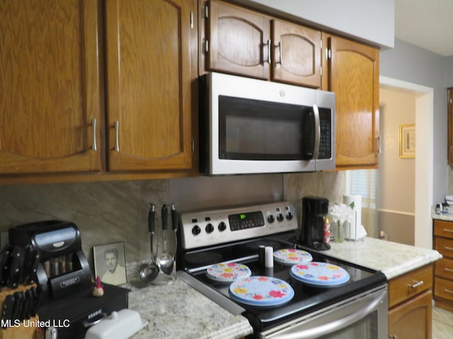 kitchen featuring light stone counters, decorative backsplash, brown cabinets, and stainless steel appliances