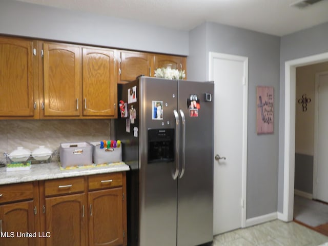 kitchen featuring visible vents, brown cabinets, light countertops, and stainless steel refrigerator with ice dispenser