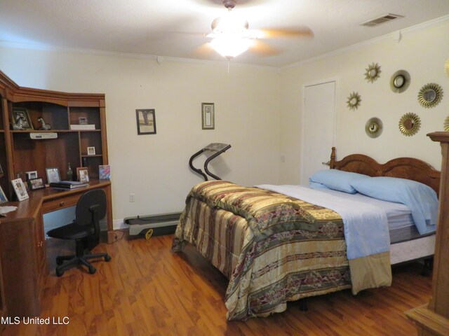 bedroom with visible vents, ornamental molding, a ceiling fan, and wood finished floors