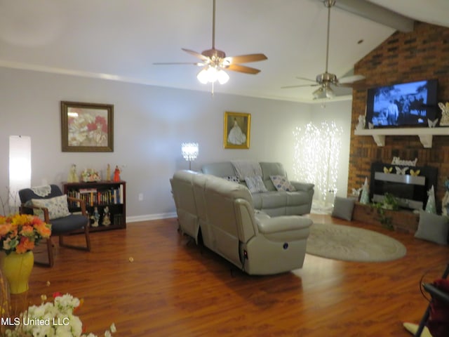 living area with wood finished floors, baseboards, lofted ceiling with beams, a fireplace, and ceiling fan