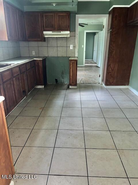 3916 Oakhill Dr, Jackson, MS 39206 - kitchen with under cabinet range hood, light countertops, light tile patterned floors, and decorative backsplash