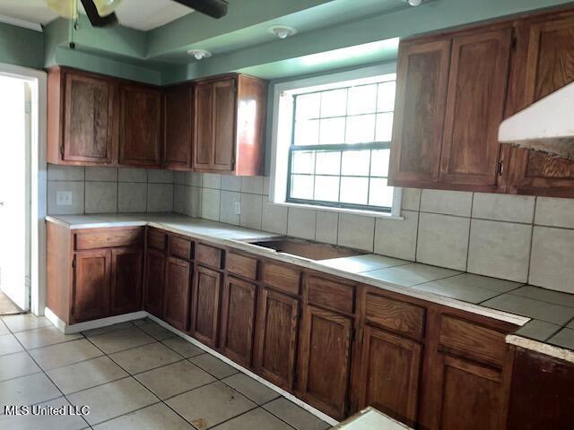 3916 Oakhill Dr, Jackson, MS 39206 - kitchen featuring backsplash, a ceiling fan, light tile patterned floors, and brown cabinets