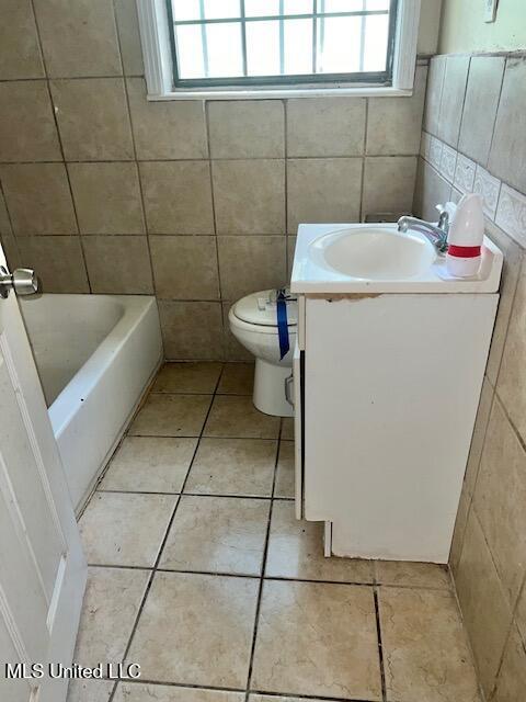 3916 Oakhill Dr, Jackson, MS 39206 - full bath featuring vanity, tile patterned flooring, plenty of natural light, a tub to relax in, and tile walls