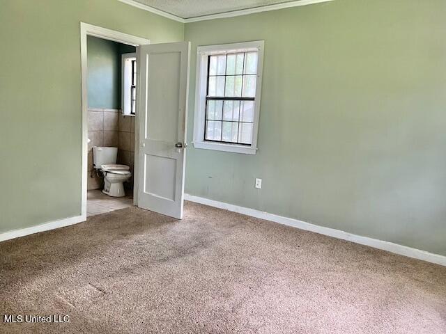 3916 Oakhill Dr, Jackson, MS 39206 - unfurnished bedroom featuring crown molding, carpet, and connected bathroom