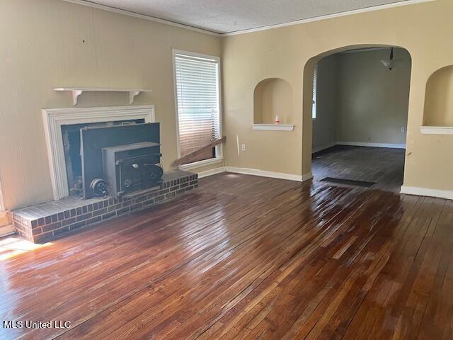 3916 Oakhill Dr, Jackson, MS 39206 - unfurnished living room with crown molding, wood-type flooring, healthy amount of natural light, arched walkways, and a wood stove