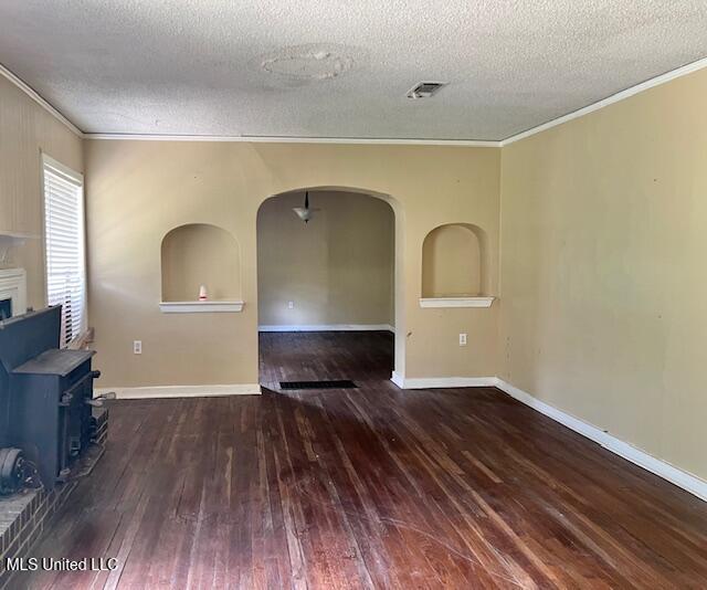 3916 Oakhill Dr, Jackson, MS 39206 - unfurnished living room featuring ornamental molding, a textured ceiling, wood-type flooring, arched walkways, and a wood stove