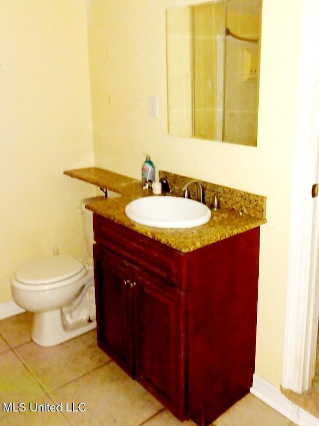 bathroom with toilet, vanity, and tile patterned floors