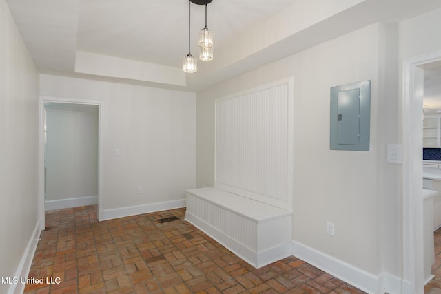 interior space featuring brick floor, electric panel, baseboards, and a raised ceiling