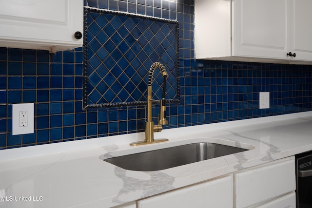 kitchen with light stone counters, a sink, white cabinetry, and tasteful backsplash