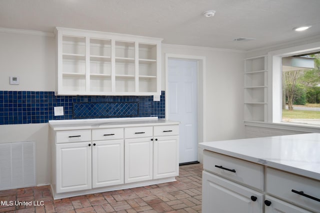 kitchen with open shelves, ornamental molding, brick floor, and visible vents