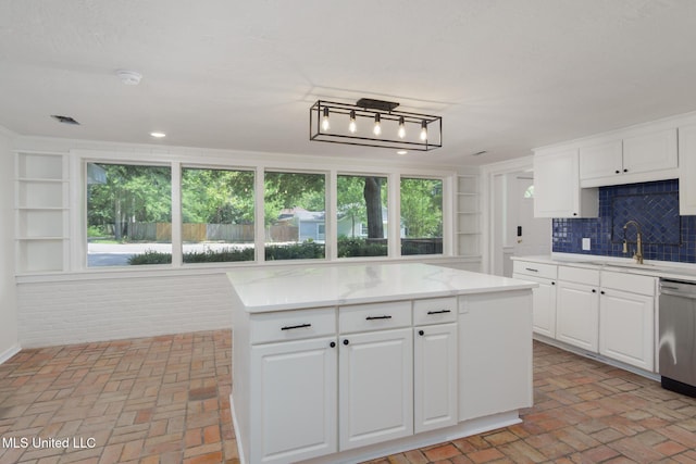 kitchen with brick floor, white cabinets, a kitchen island, and stainless steel dishwasher