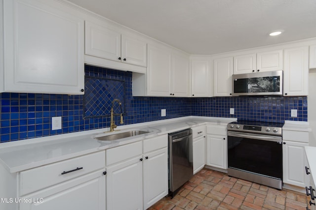 kitchen with a sink, white cabinetry, light countertops, appliances with stainless steel finishes, and decorative backsplash