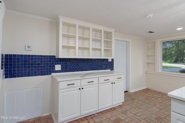 kitchen featuring brick floor, visible vents, light countertops, ornamental molding, and open shelves