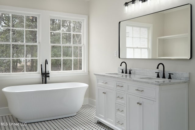 bathroom featuring double vanity, a freestanding tub, baseboards, and a sink