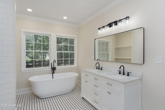 bathroom featuring double vanity, a freestanding tub, crown molding, and a sink