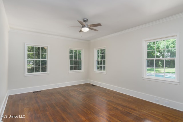 empty room featuring dark wood-type flooring, visible vents, crown molding, and baseboards